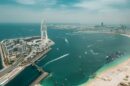 Aerial view of the Dubai waterfront with a Ferris wheel, beach and towers