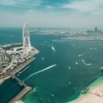 Aerial view of the Dubai waterfront with a Ferris wheel, beach and towers
