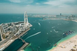 Aerial view of the Dubai waterfront with a Ferris wheel, beach and towers
