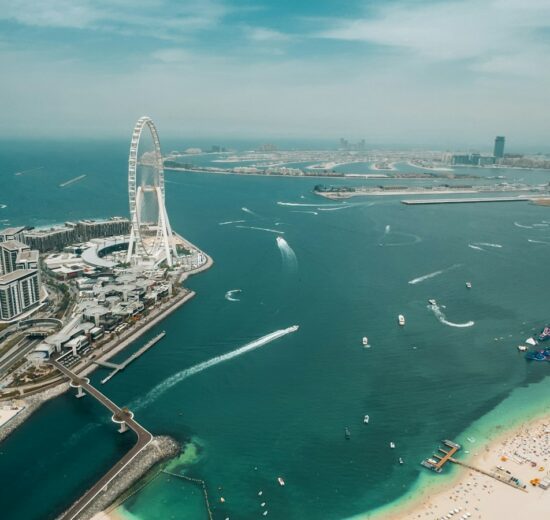 Aerial view of the Dubai waterfront with a Ferris wheel, beach and towers