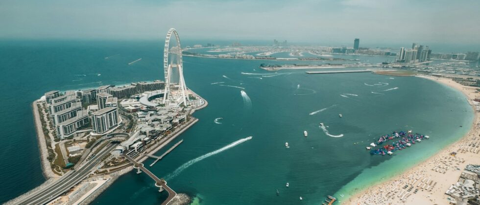 Aerial view of the Dubai waterfront with a Ferris wheel, beach and towers