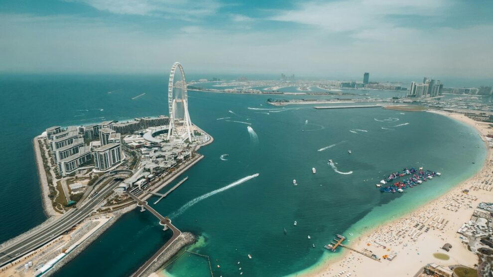 Aerial view of the Dubai waterfront with a Ferris wheel, beach and towers