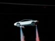 White new Tesla Roadster airborne at night with cold-gas thrusters firing beneath the wheels