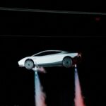 White new Tesla Roadster airborne at night with cold-gas thrusters firing beneath the wheels