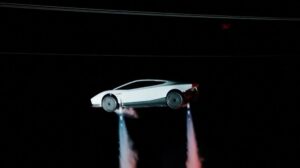 White new Tesla Roadster airborne at night with cold-gas thrusters firing beneath the wheels